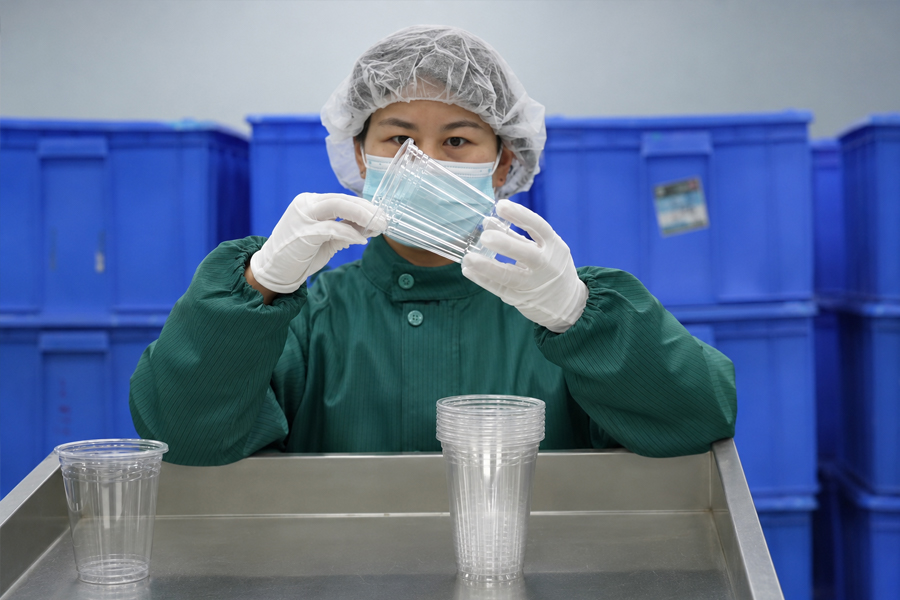 Quality inspector checking the shape, rim and surface condition of PET cold cups